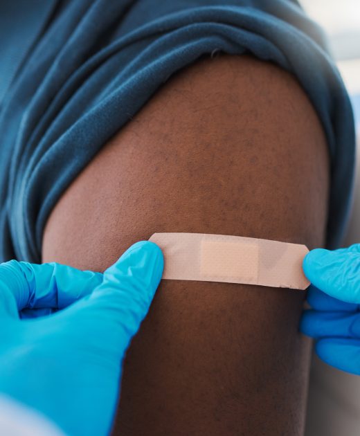 Closeup of young, healthy males arm with bandage after covid vaccine shot from medical doctor. Male patient wearing first aid plaster after medicine injection treatment from healthcare professional