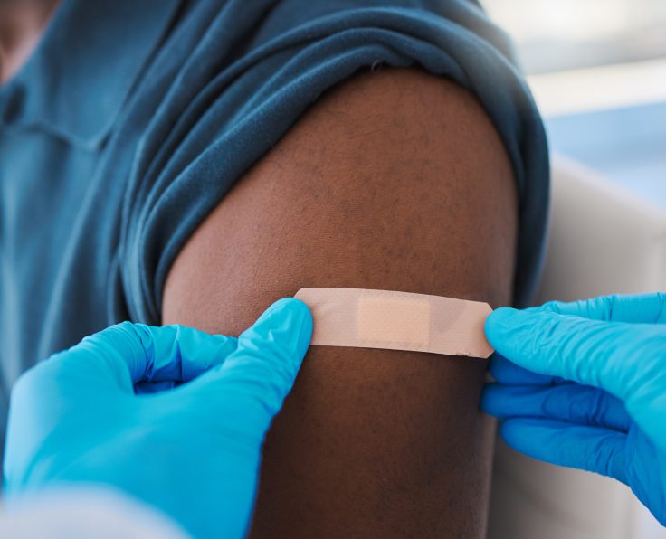 Closeup of young, healthy males arm with bandage after covid vaccine shot from medical doctor. Male patient wearing first aid plaster after medicine injection treatment from healthcare professional